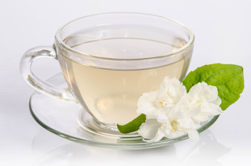 Obraz na płótnie Canvas Glass cup of Tea with jasmine flowers and leaves