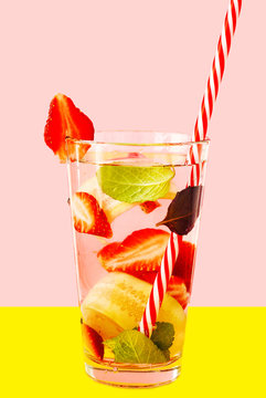 Detox water with strawberry and cucumber in glass on the pink and yellow background.
