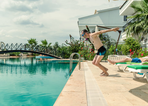 Sexy young man diving in the swimming pool in a resort