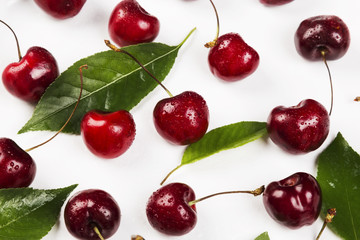 Ripe cherry and green leaves on a white background. Top view. Food background