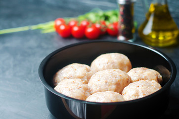 raw homemade steamed meatballs with chicken and buckwheat. black concrete background. selective focus