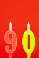 Colorful burning birthday candle  on red background