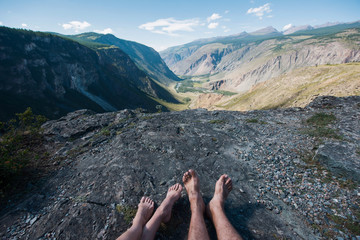 Male and female feet without shoes rest on the edge of a huge and very beautiful gorge in the...