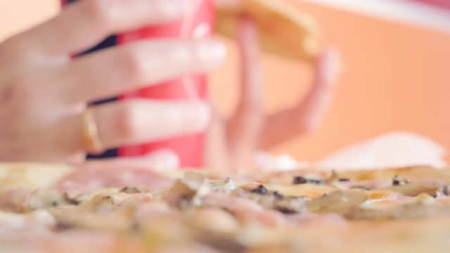 Girl eats pizza and drinks soda in cafe. Speed-up video. Bottom view shot from table