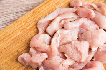 Sliced fresh chicken fillets on a wooden cutting board