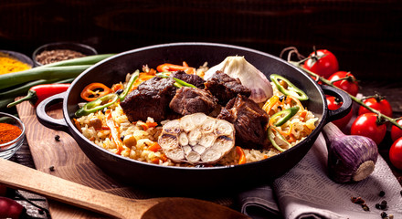 Homemade Uzbek pilaf from lamb served in cast iron cookware.