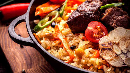 Homemade Uzbek pilaf from lamb served in cast iron cookware.