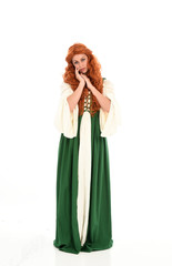 full length portrait of red haired girl wearing long green medieval gown. standing pose, isolated on white studio background.
