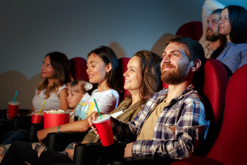 Group of friends sitting in movie theater with popcorn and drinks