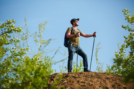Picture of man with backpack and walking sticks on hill