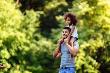 Portrait of young father carrying his daughter on his back