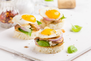 Canapes with fried mushrooms, quail egg, soft cheese and basil, beautiful appetizer for home party or event