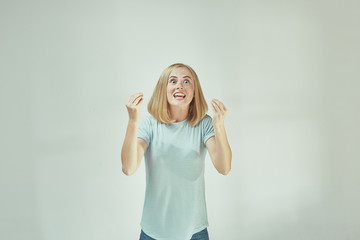 Beautiful female half-length portrait isolated on gray studio backgroud. The young emotional surprised woman