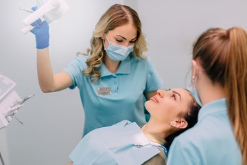 young woman dentist performs examination of patient in clinic