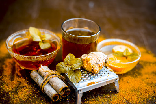 Ancient ayurveidc home remedy for common cold: Grated ginger, warm water, cinnamon powder, honey, and lemon juice in a transparent glass on wooden surface.