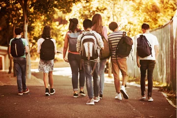 Foto auf Acrylglas Schule Rückansicht von Schulkindern, die auf dem Campus auf der Straße gehen