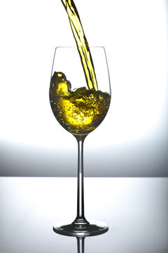 wine being poured in tall wine glass with splash and bubbles