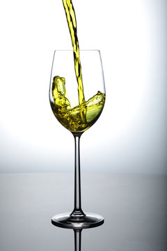 wine being poured in tall wine glass with splash and bubbles