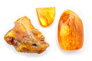 Amber. Three beautiful transparent pieces of yellow amber with holes on a white background. Frozen resin with patterns and inclusions inside. A natural mineral for jewelers. Crystal. Sun Stone