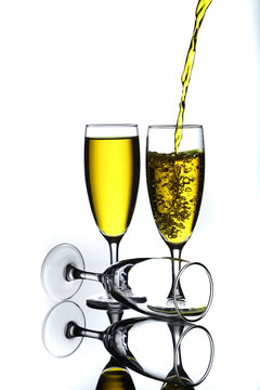 wine glasses full of yellow wine being poured with bubbles