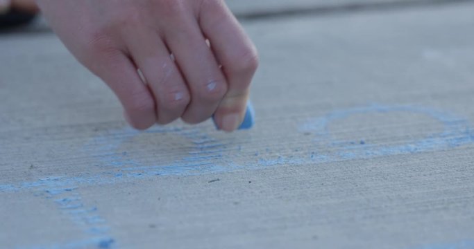 Childs hand uses sidewalk chaulk - outdoor summer activites