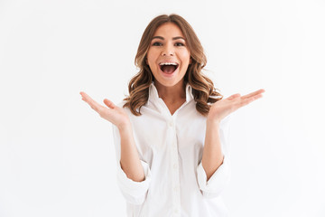 Portrait of excited young woman with long brown hair screaming and throwing up hands, isolated over white background in studio