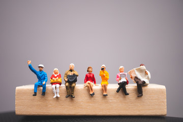 Miniature people sitting on wooden block using as business and social concept