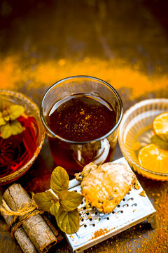 Ancient ayurveidc home remedy for common cold: Grated ginger, warm water, cinnamon powder, honey, and lemon juice in a transparent glass on wooden surface.