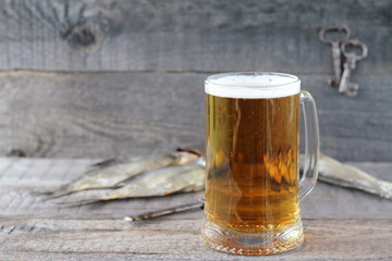 A mug of  light beer and dry fish on a wooden background.