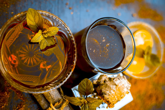 Ancient ayurveidc home remedy for common cold: Grated ginger, warm water, cinnamon powder, honey, and lemon juice in a transparent glass on wooden surface.