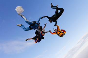Fototapeta na wymiar Group of skydivers is in the sky. Friends are falling with tandem-passenger girl.