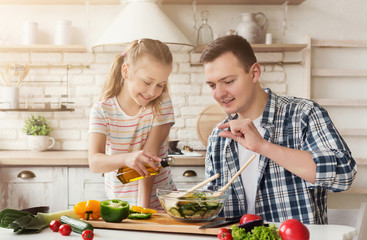 Dad and little daughter cooking in kitchen at home