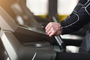 Unrecognizable man in gym running on treadmill