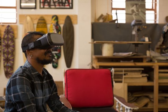 Man wearing VR glasses while sitting in workshop