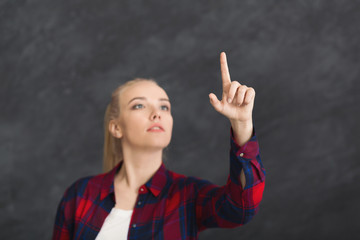 Young woman pointing on virtual object