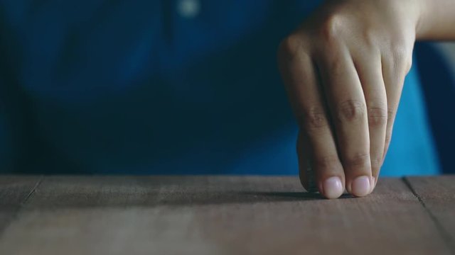 Woman wearing a blue shirt is are stacking coins on a brown wooden table. The concept of saving money.
