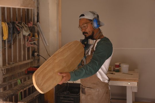 Man examining a skateboard in workshop