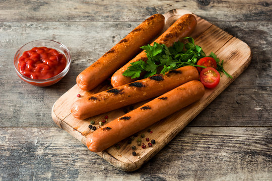 Grilled sausages and ketchup on wooden table

