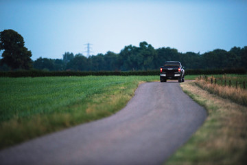 Pickup truck driving on country road in evening.