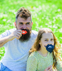 Father posing with lips and child posing with beard photo booth attribute. Gender roles concept....