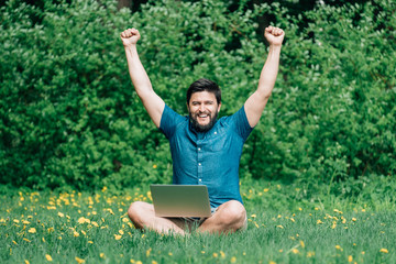 Happy excited man with laptop raised hands up celebrate success