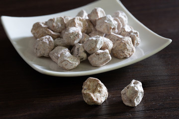 Dried Plums salted in white dish and out of dish on brown wooden