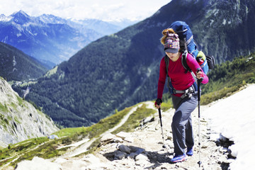 Trek around Mont Blanc. The girl is walking along the trail with a backpack.