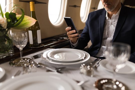 Businessman using mobile phone in private jet - Powered by Adobe