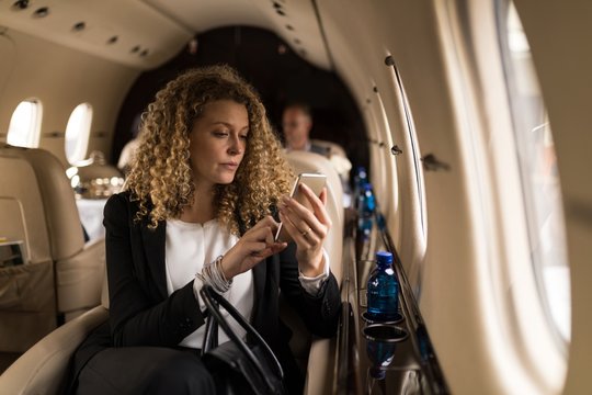 Businesswoman using mobile phone in private jet