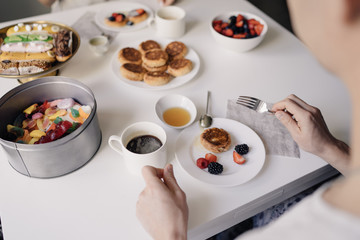 the couple has breakfast with cheese cakes and berries