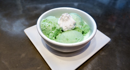 green ice cream gelato in a white bowl whipped cream