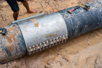 worker lock Cast aluminium cover & PVC Plastic water pipe broken, 600 mm. diameter band with torque bolt screw. Water PVC Plastic Pipes in Ground during Plumbing Construction site.