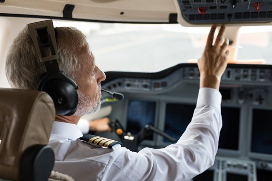 Male pilot pushing button in cockpit