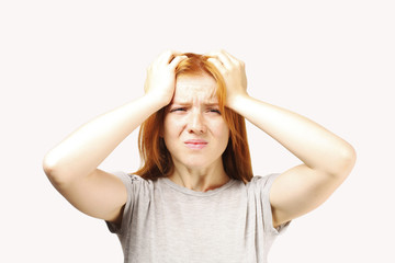 Beautiful redheaded young woman experiencing severe migraine writhing with pain. Pretty female feeling headache holding head. Nonverbal behavior, body language. White background, close up, copy space.
